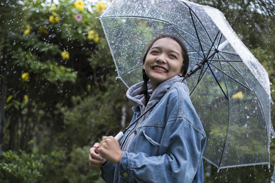 Full length of happy woman standing on wet rainy day