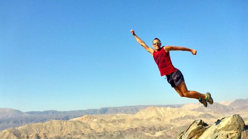 Full length of man jumping over landscape against sky