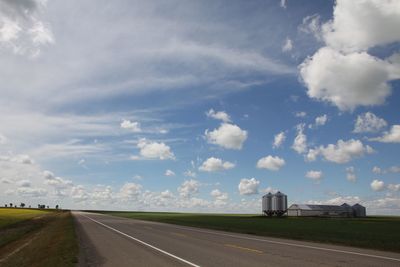 Road passing through landscape against cloudy sky