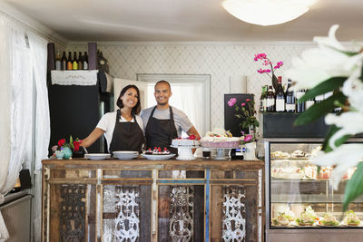 Portrait of smiling bakers standing at cafe counter