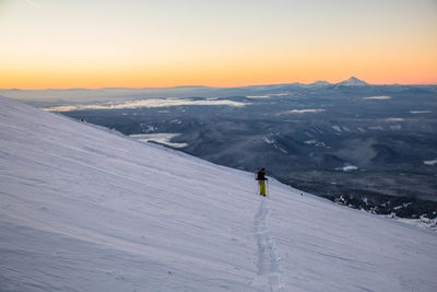 Man skiing on snowcapped mountain during sunset