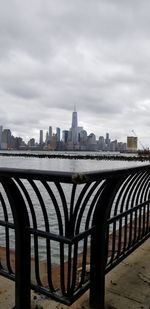 View of buildings by river against cloudy sky