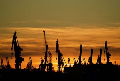 Silhouette of commercial dock against sky during sunset