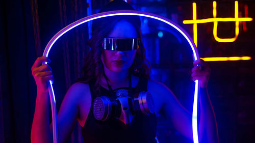 Caucasian woman in sunglasses posing in neon studio