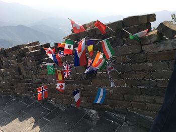 Various national flag on old brick wall against mountains