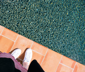 Low section of woman standing in front of swimming pool