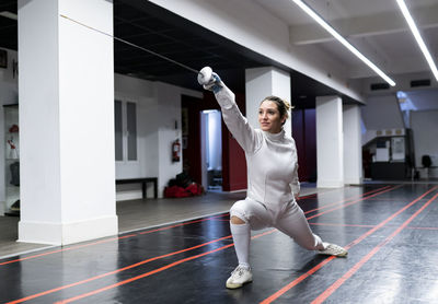 Woman in fencing outfit practicing at gym