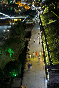 High angle view of people walking on illuminated street at night