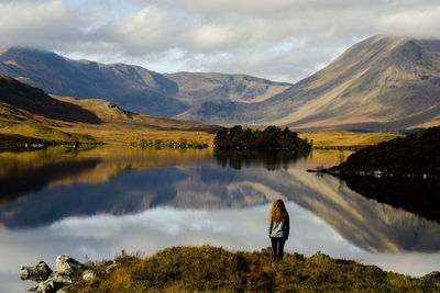 Rear view of man standing by lake against sky