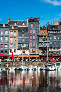 Sailboats moored on canal by buildings in city against sky