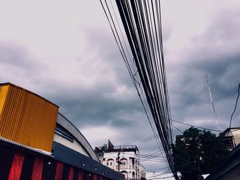 Low angle view of cables and buildings against sky