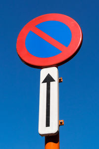 Low angle view of road sign against blue sky