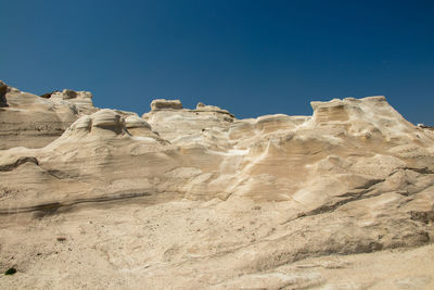 Low angle view of rock formation against clear blue sky