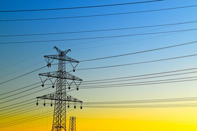 Low angle view of silhouette electricity pylon against sky during sunset