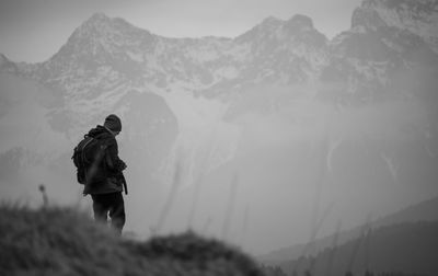 Rear view of hiker standing against mountains during winter