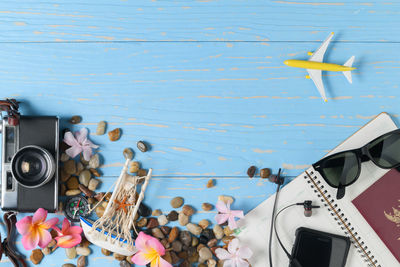 Directly above shot of spiral notebook with technologies and travel equipment on blue table