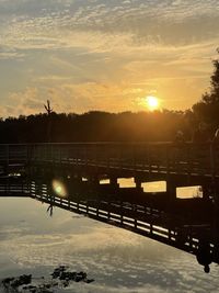 Silhouette bridge over river against sky during sunset