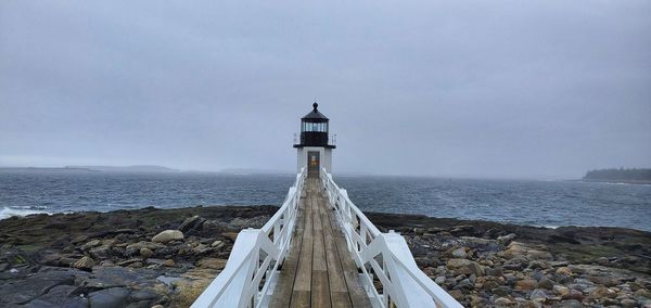 Lighthouse by sea against sky