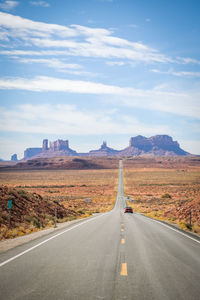 Road leading towards mountain against sky