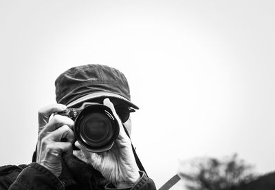 Man photographing from camera against clear sky