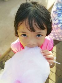 Cute girl eating cotton candy while standing outdoors