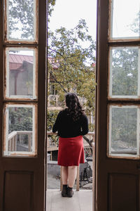 Rear view of woman standing by window