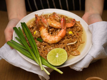 Midsection of person holding food in plate on table