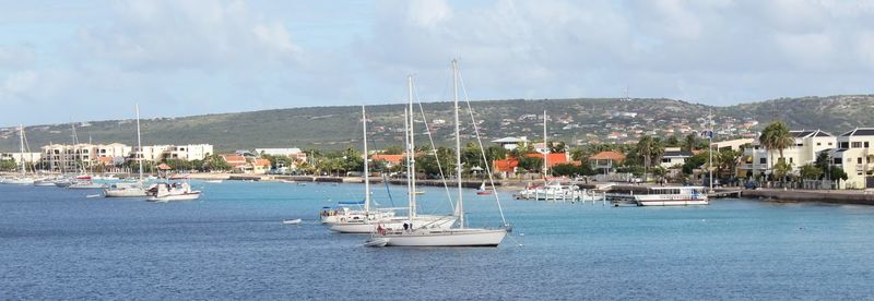 Boats moored at harbor against sky