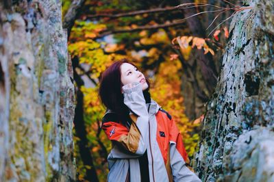 Young woman standing by tree