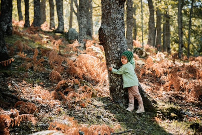 Portrait of girl hugging by tree trunk in forest