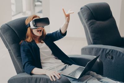 Cheerful woman using virtual reality simulator at home