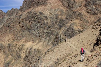 Rear view of person walking on rocky mountain