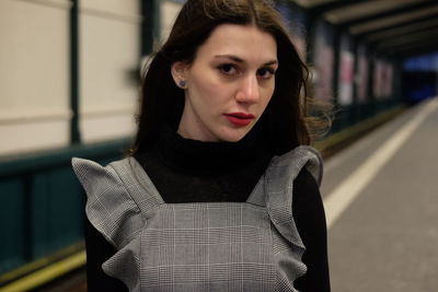 Close-up portrait of young woman standing at railroad station platform