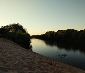 Scenic view of lake against clear sky at sunset