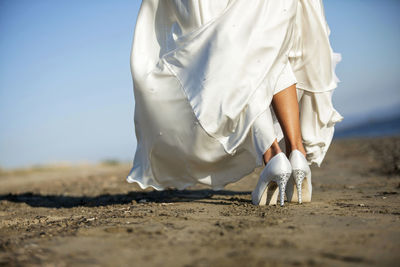 Low section of woman wearing dress while walking on landscape