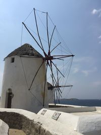 Traditional windmill by sea against sky