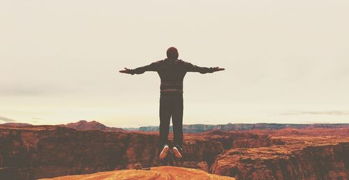 Full length of woman standing on cliff against sky