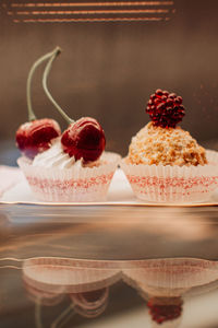 Sweet tiny cakes with fluffy cream and red cherries