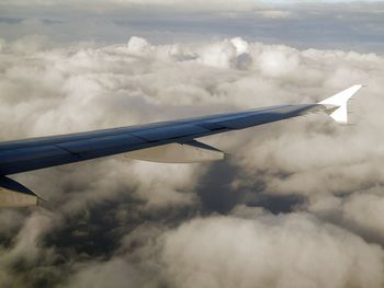 Airplane wing against cloudy sky