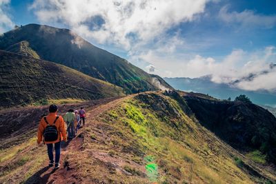 Rear view of people walking on mountain against sky