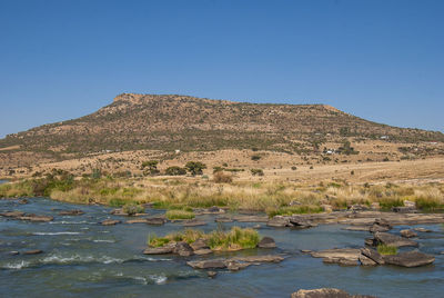 Scenic view of lake and mountains against clear blue sky