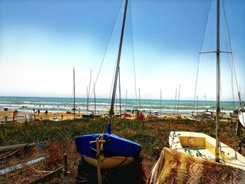 Sailboats moored on beach against clear sky