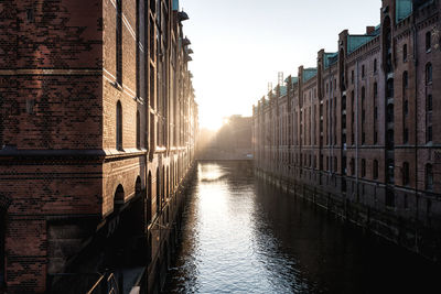 Canal amidst buildings during sunset