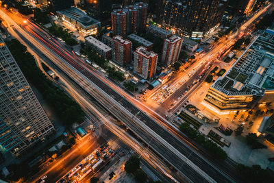 High angle view of illuminated street amidst buildings in city at night