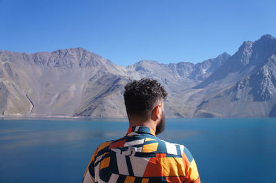 Rear view of man looking at mountain against sky