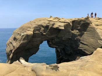 Rock formation on beach against sky