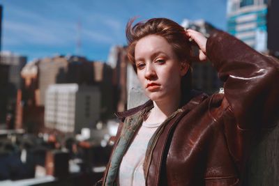 Portrait of young woman against buildings and sky