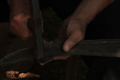 Cropped hand hammering on metal at workshop