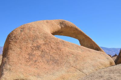 Low angle view of rocks against clear blue sky