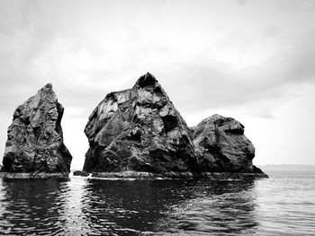 Rock formation in sea against sky